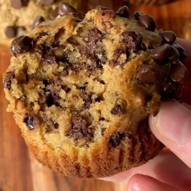 A plate of healthy peanut butter banana muffins with ripe bananas in the background.