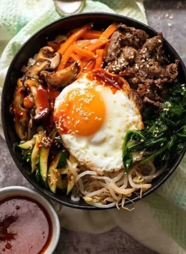 A colorful bowl of traditional Korean Bibimbap with vegetables, rice, and sauce.