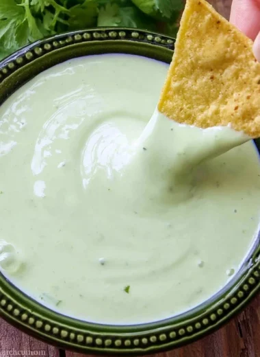A bowl of cilantro lime cream garnished with fresh cilantro leaves