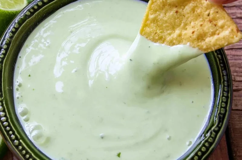 A bowl of cilantro lime cream garnished with fresh cilantro leaves