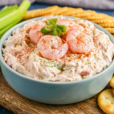 Creamy shrimp dip served in a bowl with fresh herbs and crackers