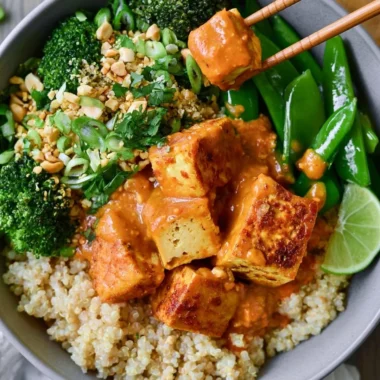 Cozy Thai peanut tofu quinoa bowl topped with fresh vegetables and peanut sauce