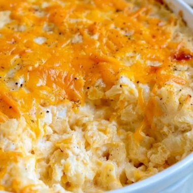 Cheesy hashbrown casserole served in a dish, garnished and ready to enjoy.