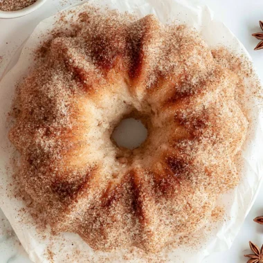 Cozy apple cider donut cake topped with cinnamon and served on a rustic plate