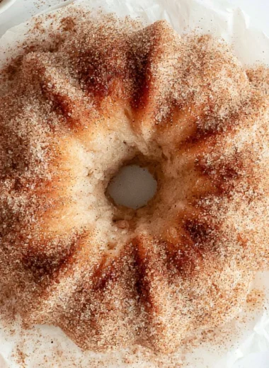 Cozy apple cider donut cake topped with cinnamon and served on a rustic plate