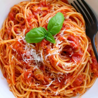 Delicious cozy pasta tomato dish garnished with fresh basil and Parmesan cheese.