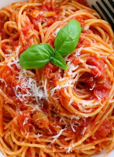 Delicious cozy pasta tomato dish garnished with fresh basil and Parmesan cheese.