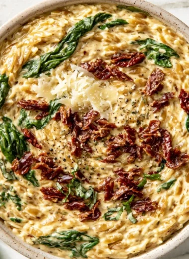 Cozy Tuscan garlic orzo served in a rustic bowl, garnished with herbs.
