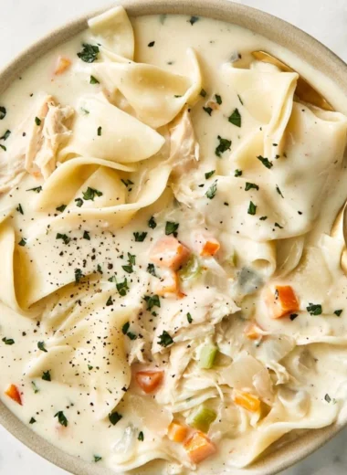Bowl of creamy chicken soup with fresh herbs and vegetables