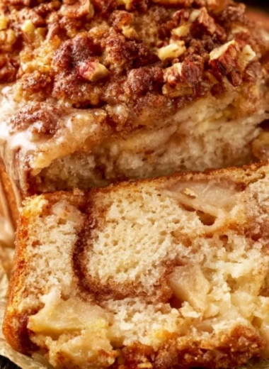 Loaf of moist cinnamon apple bread with slices on a wooden board