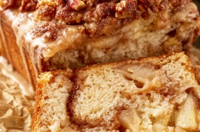 Loaf of moist cinnamon apple bread with slices on a wooden board