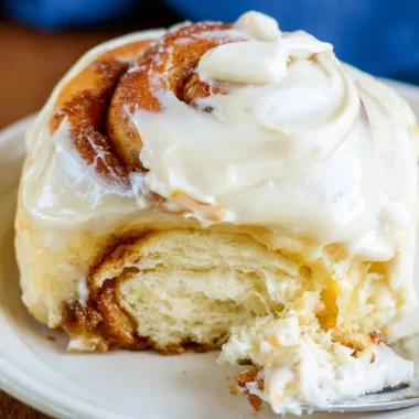 Freshly baked sourdough cinnamon rolls with creamy glaze on a cozy table.
